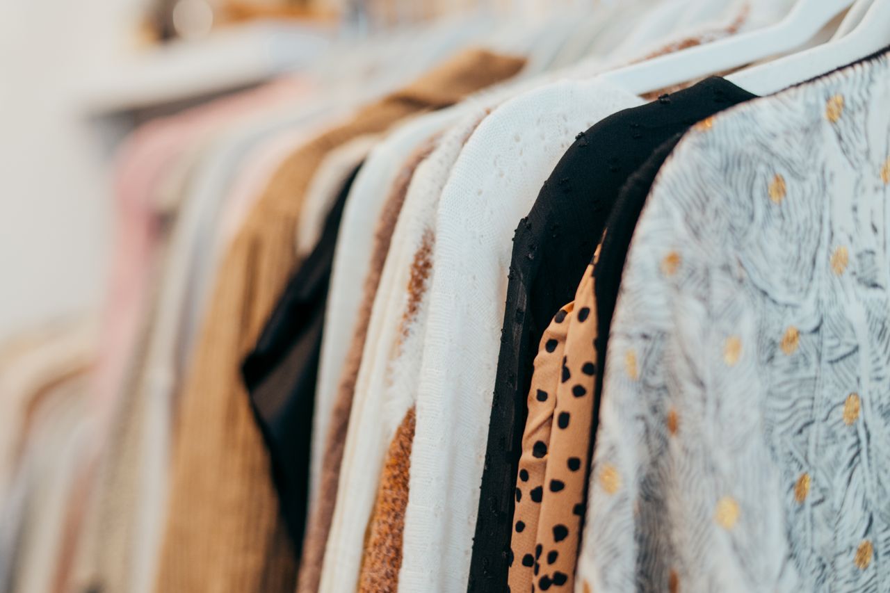 Offerings A close-up view of fashionable clothes hanging on racks in a boutique setting, showcasing various patterns and textures.