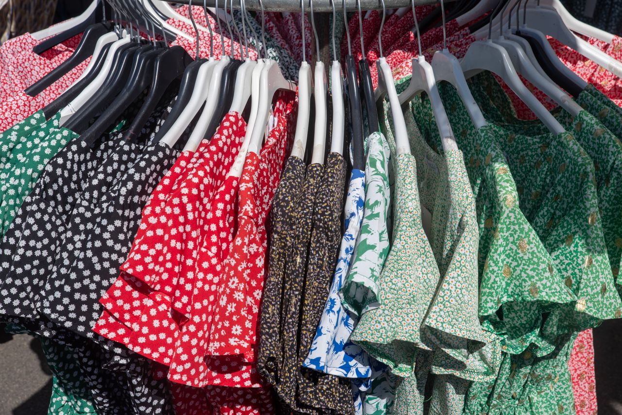 Offerings Vibrant collection of floral and patterned dresses hanging on a clothing rack, showcasing diverse styles.